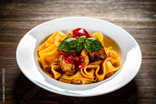 Pasta with meatballs in tomato sauce on wooden table 
