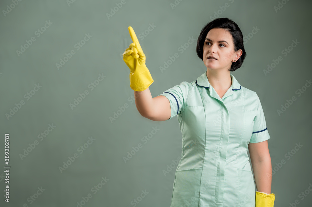 Young cleaning woman wearing a green shirt and yellow gloves presses a virtual button Young cleaning woman wearing a green shirt and yellow gloves presses a virtual button