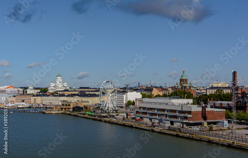Helsinki cityscape shot from water with white Helsinki Cathedral, red Uspenski Cathedral, big Ferry Wheel and black city roofs, Finland.