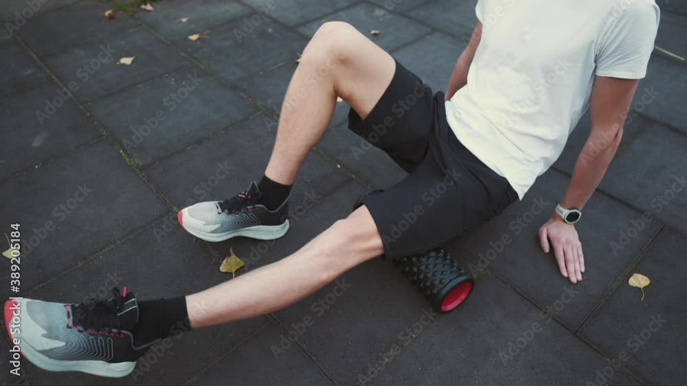 Caucasian man athlete doing exercises on myofascial roller massage leg