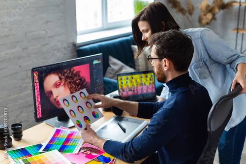 Photographer and graphic designer working in office with laptop, monitor, graphic drawing tablet and color palette. Creating team discussing ideas in advertising agency. Retouching images. Teamwork.