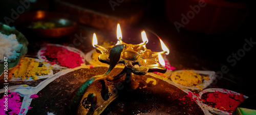 A glowing Multi Flame Lamp commonly known as Panchapradip. A holy thing used as an offering to God for worship. Surrounded by colourful Rangoli. photo