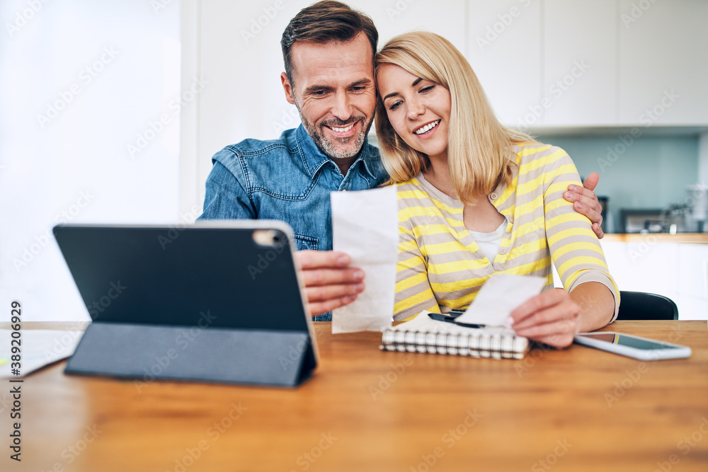 Happy couple planning home budget sitting together Happy couple planning home budget sitting together