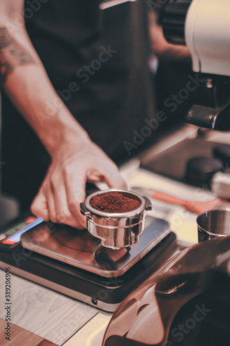 Barista is weighing the roasted coffee on digital scale before making coffee .