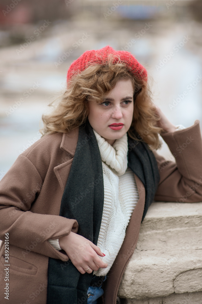 Portrait of a cute girl in a red hat and brown coat outdoors. Portrait of a cute girl in a red hat and brown coat outdoors.