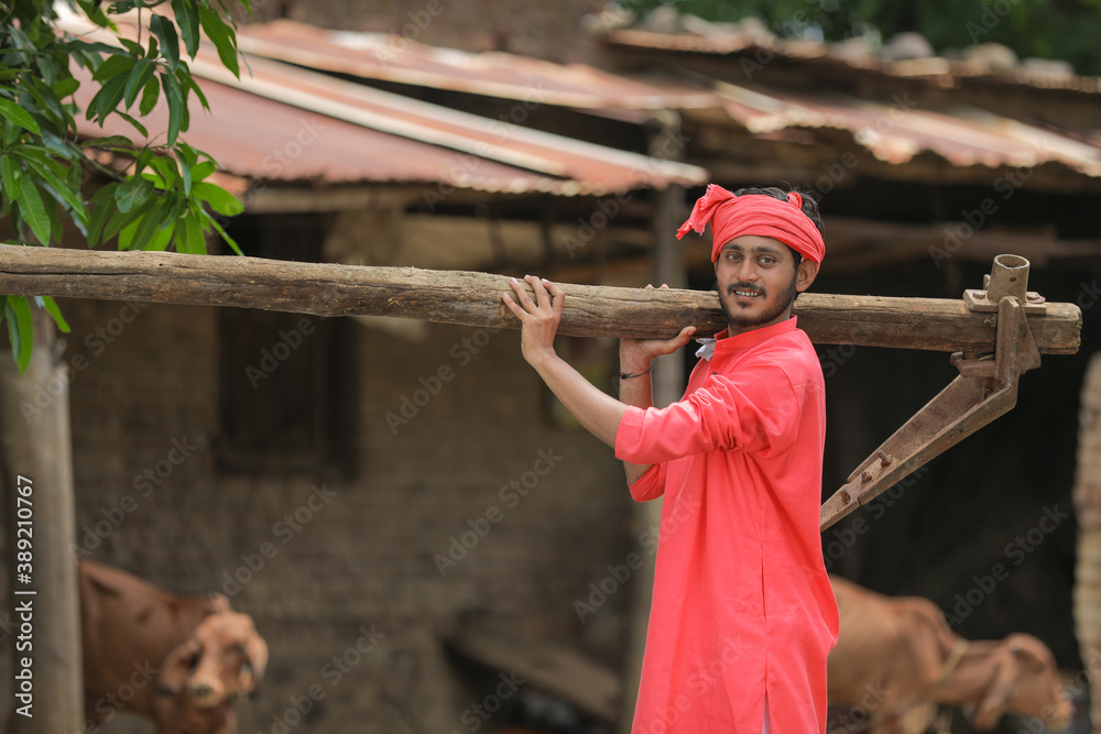 Indian farmer in traditional wear and holding farm equipment in hand