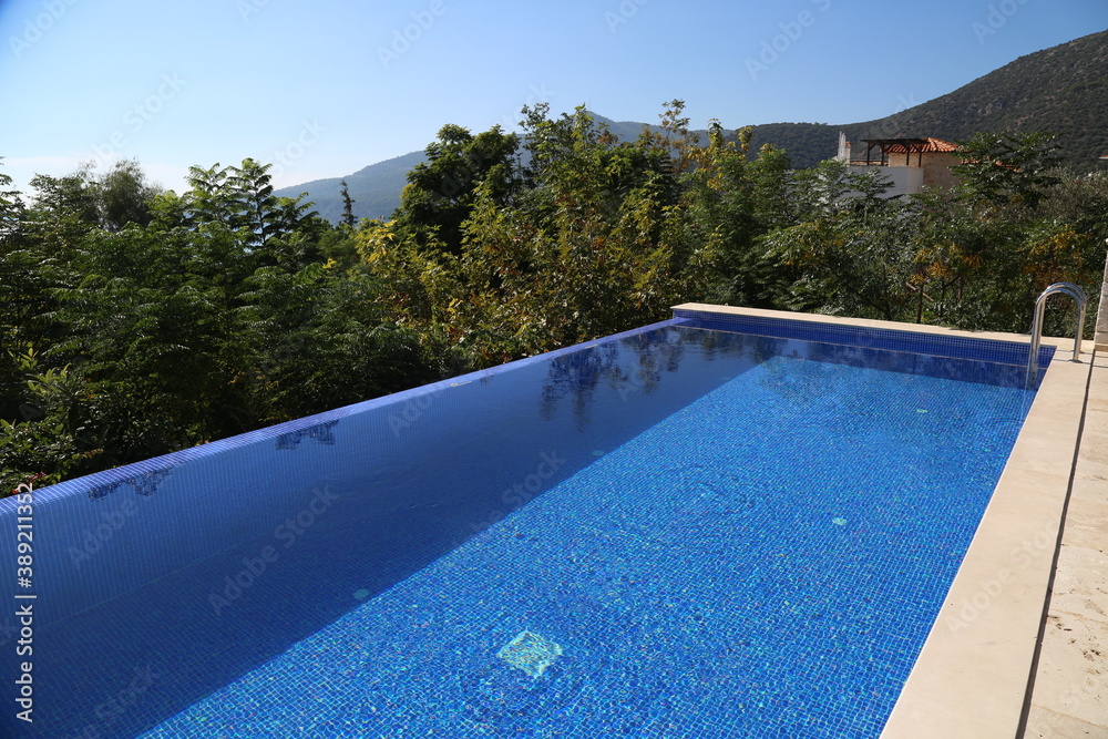 Beautiful infinity pool at the luxury villa in Turkey. Swimming pool with black sun chairs.