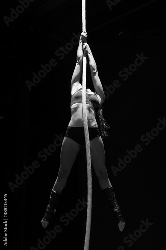 Young woman doing acrobatics on a black background