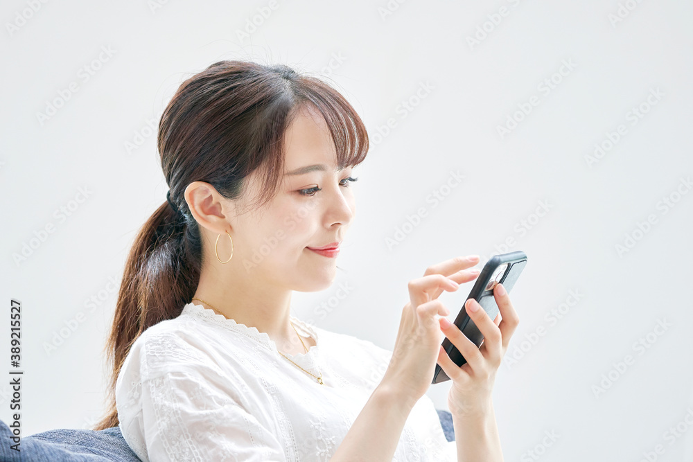 リビングでスマートフォンを使う女性 リビングでスマートフォンを使う女性