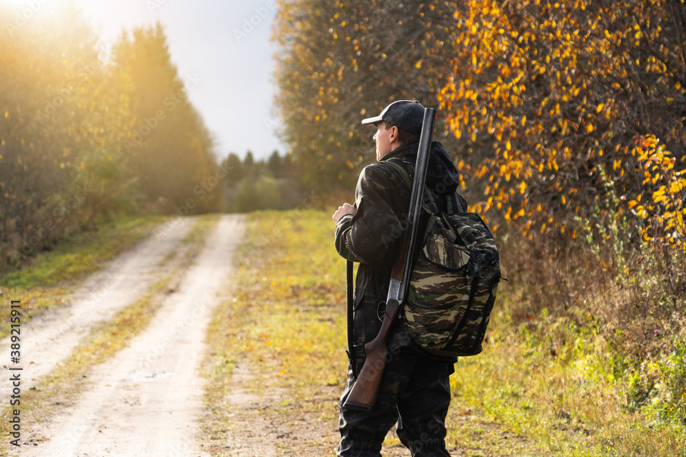 Hunter with a gun and a backpack in the forest	