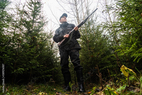 Hunter with a gun and a backpack in the forest 