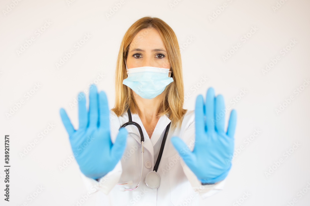 Covid19, coronavirus, healthcare and doctors concept. Serious female doctor in medical mask, with stethoscope and white coat, show stop sign. Covid19, coronavirus, healthcare and doctors concept. Serious female doctor in medical mask, with stethoscope and white coat, show stop sign.