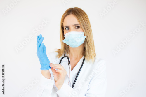 Beautiful female doctor or nurse wearing protective mask and latex or rubber gloves on white background with copy space. Health care concept