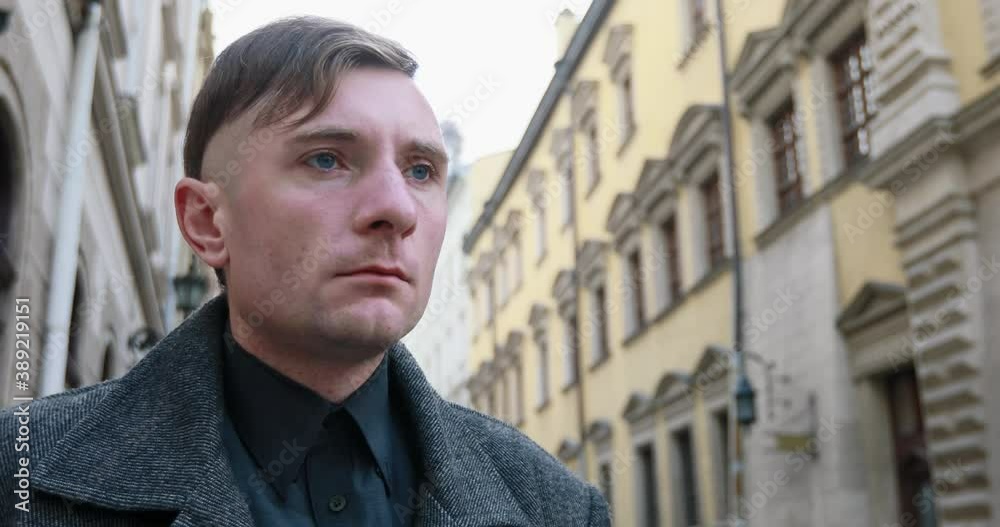 A man in a coat walks down the street of the old town and worries A man in a coat walks down the street of the old town and worries