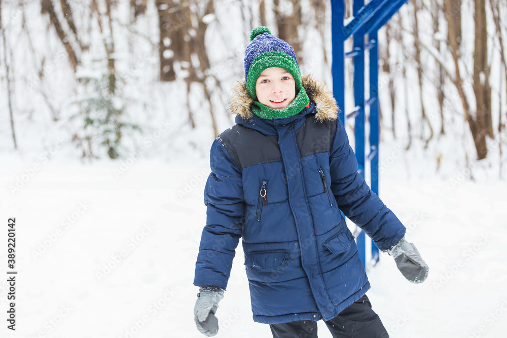 Cute young boy plays with snow, have fun, smiles. Teenager in winter park. Active lifestyle, winter activity, outdoor winter games, snowballs. Cute young boy plays with snow, have fun, smiles. Teenager in winter park. Active lifestyle, winter activity, outdoor winter games, snowballs.