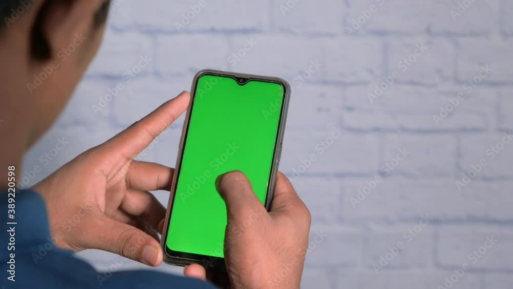 back view of man holding smart phone with green screen back view of man holding smart phone with green screen