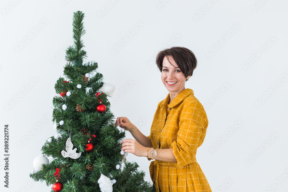 Beautiful young woman decorating a Christmas tree. Holidays and celebrations concept. Beautiful young woman decorating a Christmas tree. Holidays and celebrations concept.