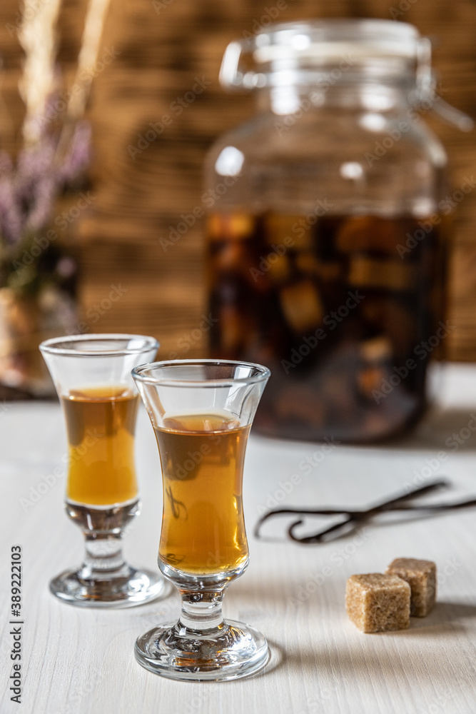Likör aus Rhabarber, Vanille, Kandiszucker und Schnaps auf weißem Tisch ...