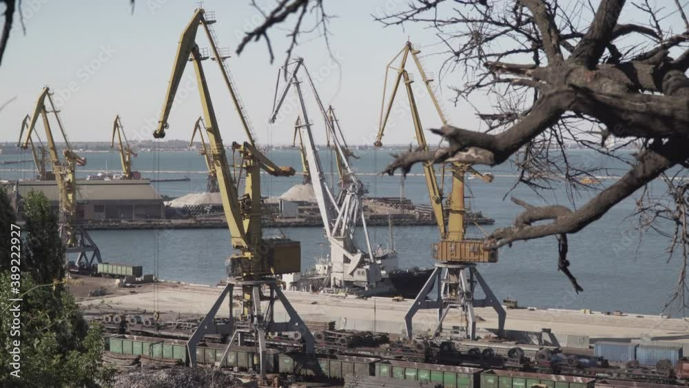 View of seaport,freight train, foreground cranes loading cargo for transportation on summer sunny day. Topic economy of the state and logistics, life near sea. View of seaport,freight train, foreground cranes loading cargo for transportation on summer sunny day. Topic economy of the state and logistics, life near sea.
