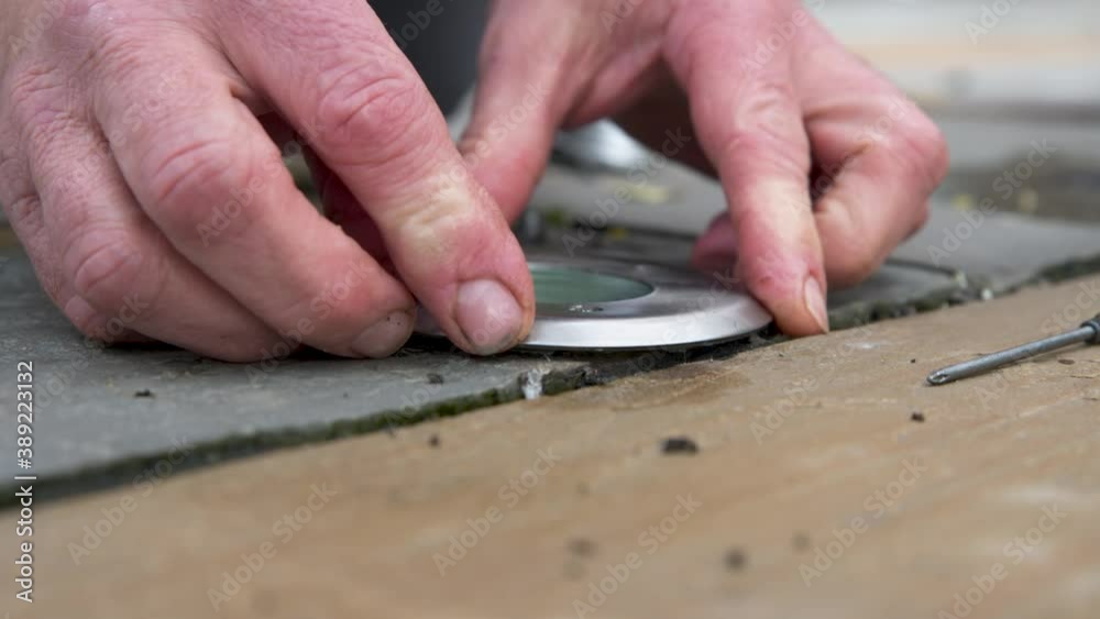Male hands assembling ground light on floor from replacing a failed bulb from bad weather. Male hands assembling ground light on floor from replacing a failed bulb from bad weather.