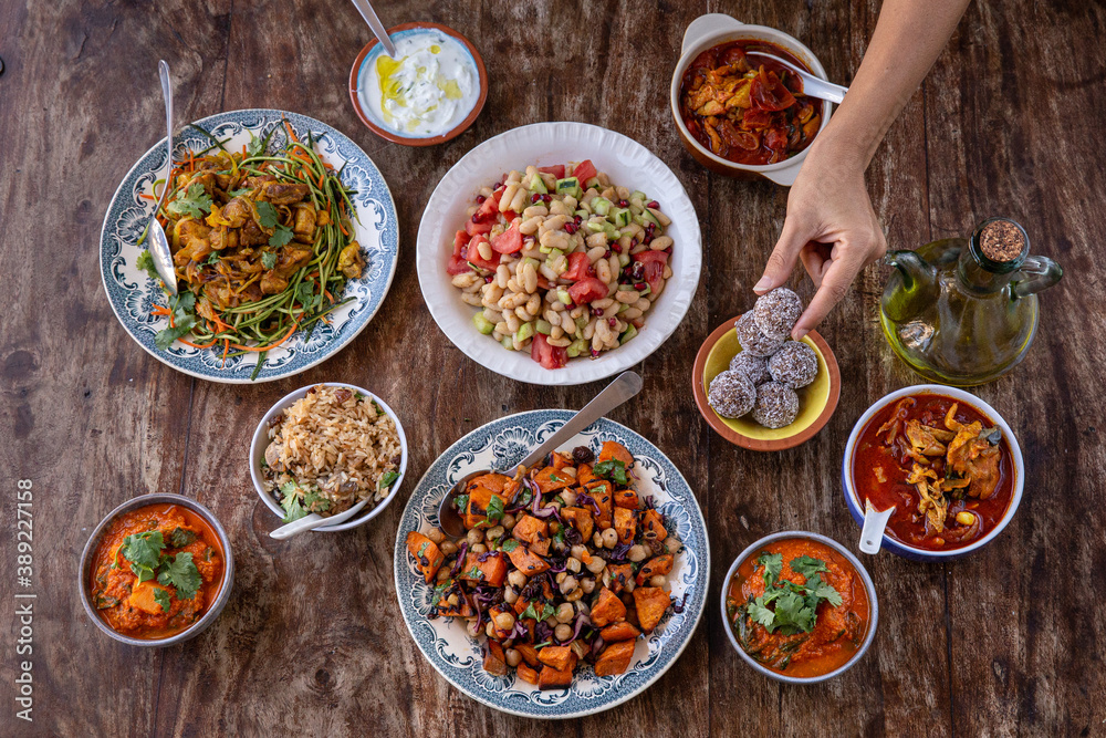 table full of healthy and colorful food with detail of hands touching asian and Mediterranean food table full of healthy and colorful food with detail of hands touching asian and Mediterranean food
