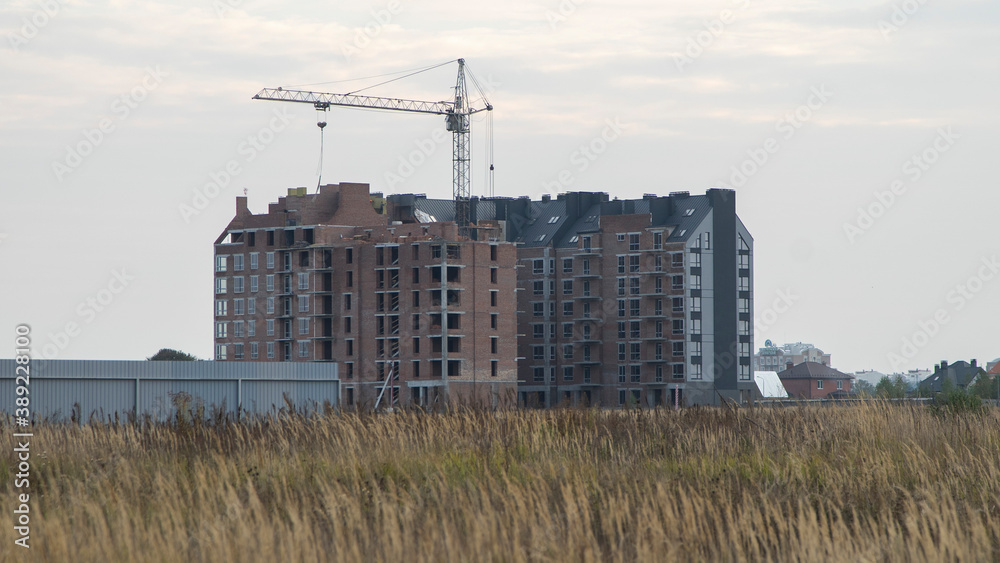 Construction of a multi-storey building outside the city. Apartment building.
Unfinished house in a field near the city.