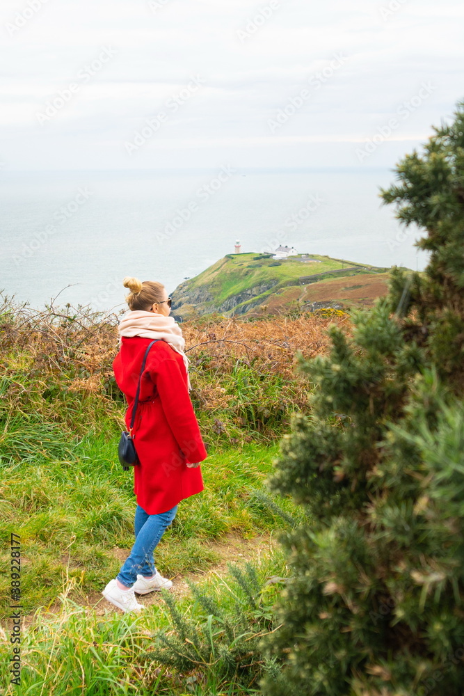 Beautiful scenery of Baily Lighthouse on Howth Head, county Dublin, Ireland. Girl in red coat in foreground