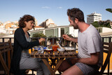 couple eating healthy food smiling on terrace with beautiful view of barcelona