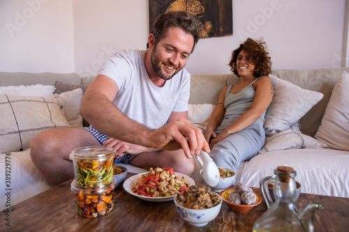 Couple eating healthy food from a delivery on the couch smiling