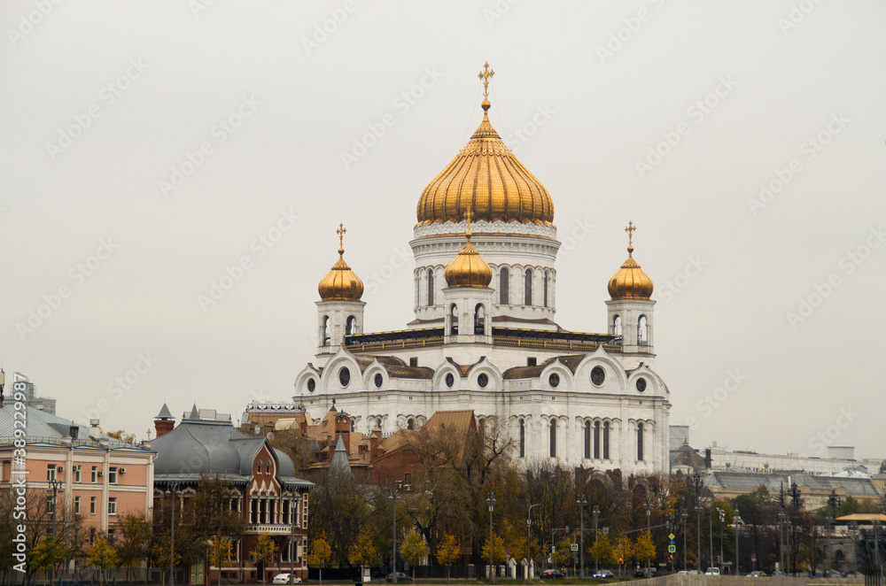 A white Temple with Golden domes against a cloudy gray sky. Moscow, Russia.