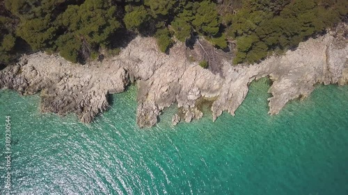 Aerial top down shot of shore cliff and turquoise sea water during sunny day