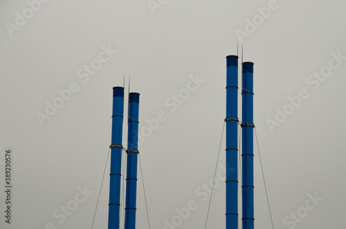 Blue factory chimneys against a gray sky. Industrial landscape.