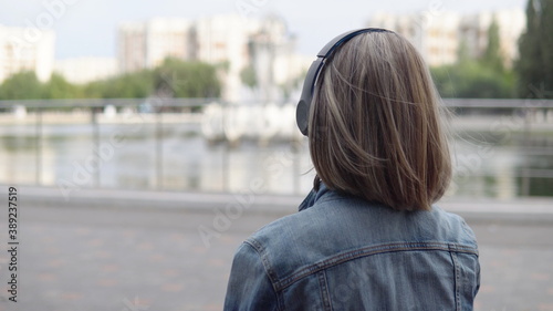 Woman sitting on a bench and listening to music through headphones