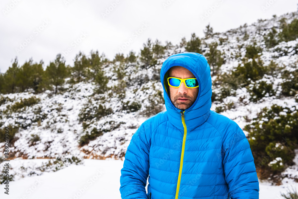 Hiker walks down the mountain during a snow covered in a down coat. Hiker walks down the mountain during a snow covered in a down coat.