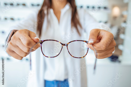 Optician giving new glasses to customer for testing and trying. Eye doctor showing patient lenses. Professional optometrist in white coat. Female doctor in ophthalmology clinic.. photo