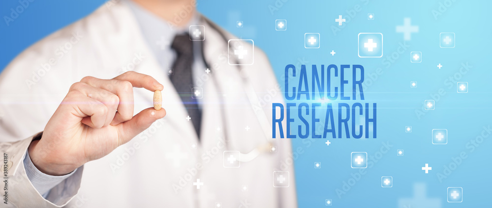 Close-up of a doctor giving a pill with CANCER RESEARCH inscription, medical concept Close-up of a doctor giving a pill with CANCER RESEARCH inscription, medical concept