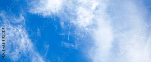 Photography airplane in the blue sky with clouds from below, high flying passenger plane with condensation trail
