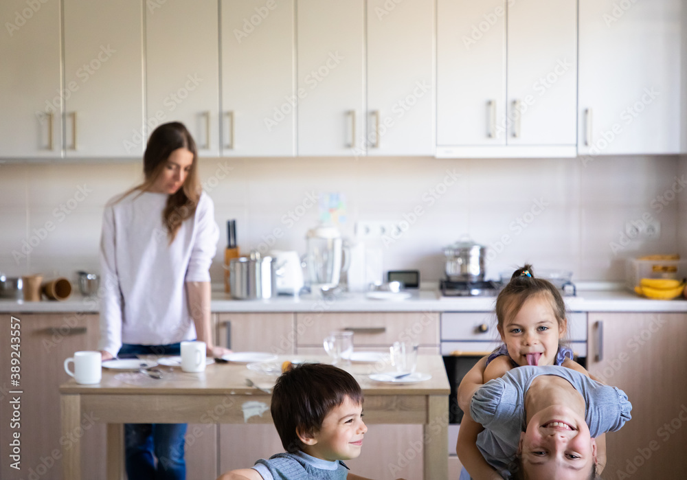 Children having fun and playing and tired mother in the messy kitchen Children having fun and playing and tired mother in the messy kitchen