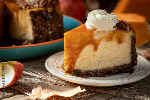 Pumpkin cheesecake. Curd cake with caramel, nuts, whipped cream, pumpkin, apples and autumn leaves on the background.