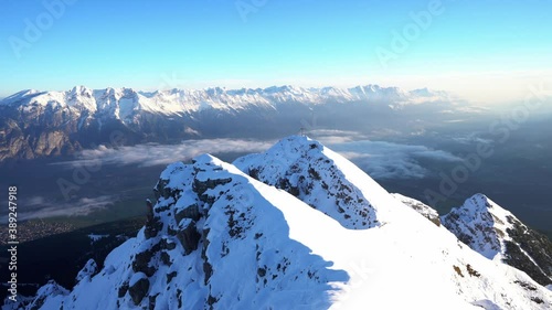 View of gorgeous pink sunrise over glacier and high mountain peaks in the Alps. The cross on top of the mountain Nockspitze. Innsbruck and the Alps are seen from the Mount.  photo