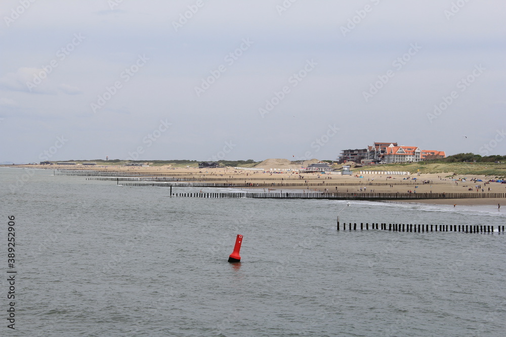 the beautiful coastline of cadzand in zeeland, the netherlands in summer with a sand beach with breakwaters along scheldt river and hotels at the dunes