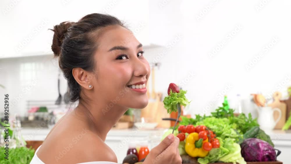 Beautiful young woman eating salad in the kitchen Beautiful young woman eating salad in the kitchen