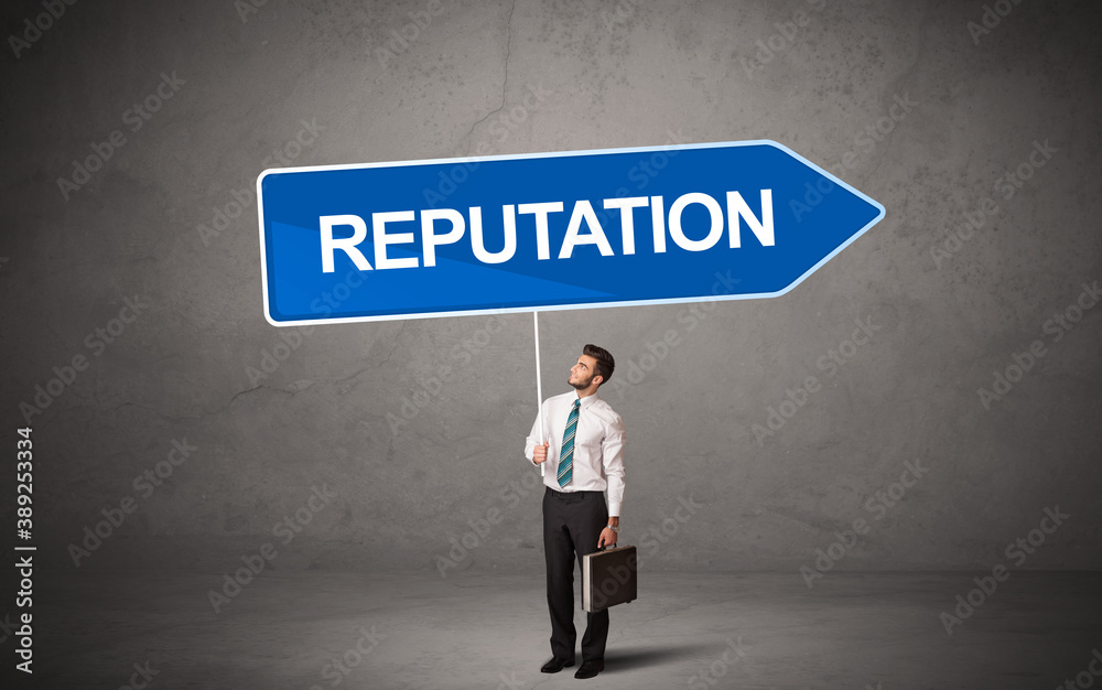 Young business person in casual holding road sign with REPUTATION inscription, new business direction concept Young business person in casual holding road sign with REPUTATION inscription, new business direction concept