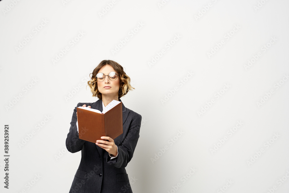 Woman at work with book in hand light background classic suit glasses head Woman at work with book in hand light background classic suit glasses head