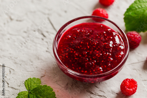 homemade raspberry jam on a concrete background with fresh raspberries, selective focus