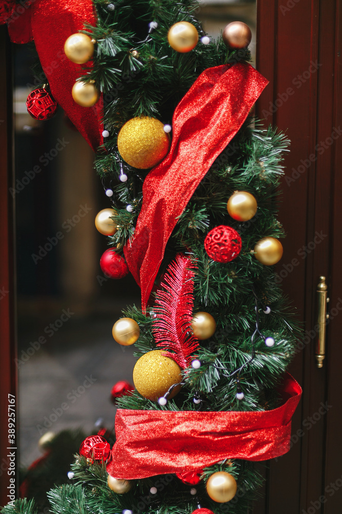Fototapeta premium Stylish christmas branches with red and gold baubles, modern ornaments on storefront or facade