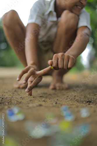 A child playing with glass marbles which is an old Indian village game. Glass Marbles are also called as Kancha in Hindi Language. photo