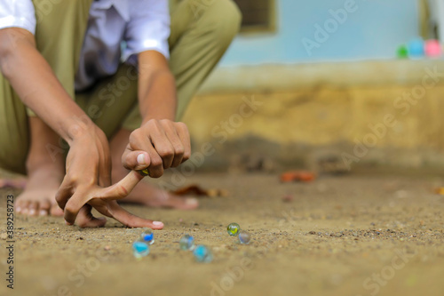 A child playing with glass marbles which is an old Indian village game. Glass Marbles are also called as Kancha in Hindi Language.