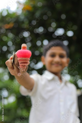 indian child playing with bhovra, Lattu, Bhovra or Bambaram is a traditional throwing top using thread, played mainly in India photo