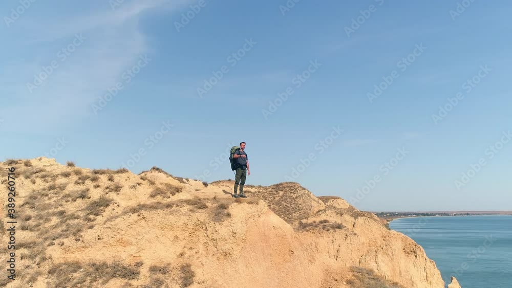 The man is standing on the mountain top against the sea